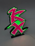 Retro Kawasaki KX logo LED lightbox glowing green on a desk